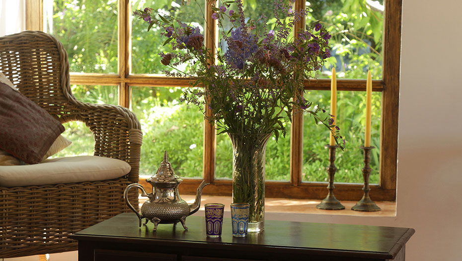 The sitting room at Casa Ana featuring a table with fresh cut purple flowers and an elegant teapot