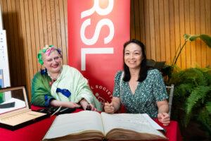 Aki Schilz signs the roll at the Royal Society of Literature alongside Director Molly Rosenberg
